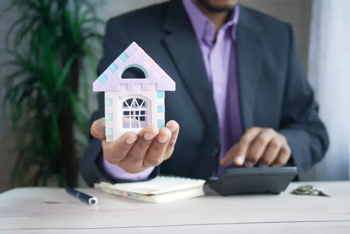 Adviser holding a small model house over a desk